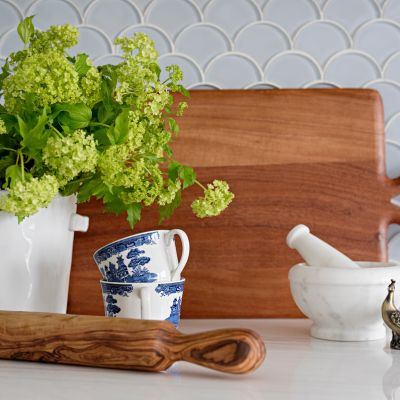 kitchen counter with blue backsplash tile, china tea cups and wooden cutting board